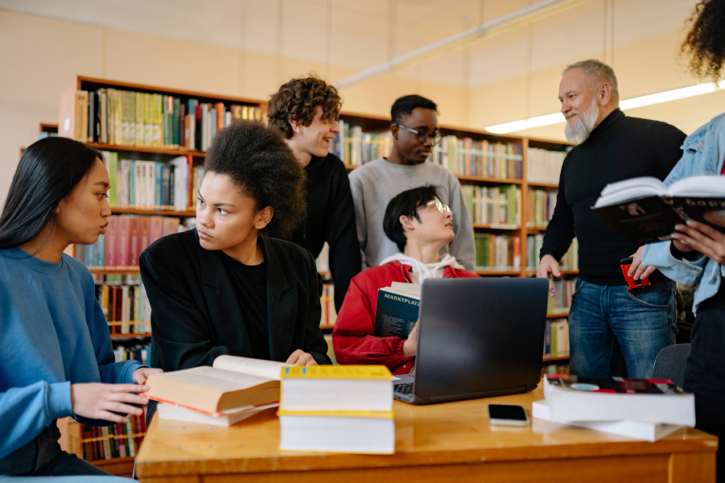 A group of university age people in a library studying and taking