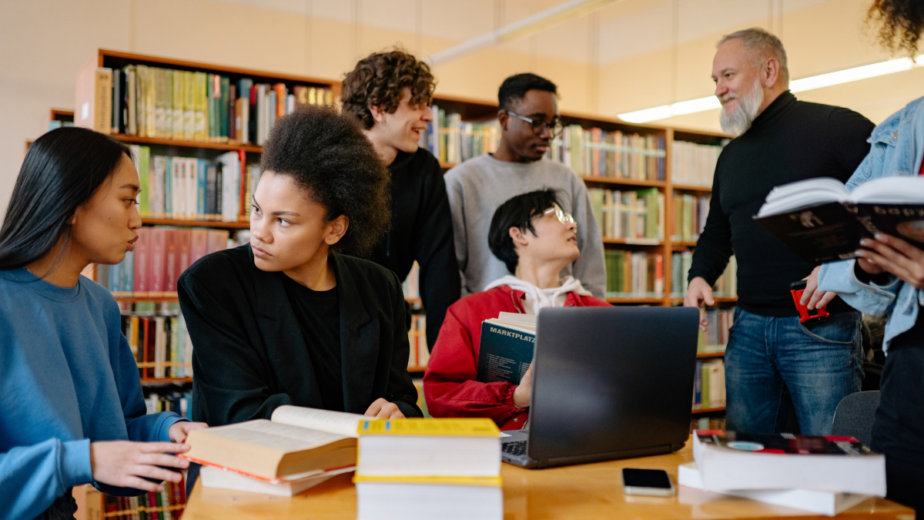 A group of university age people in a library studying and taking
