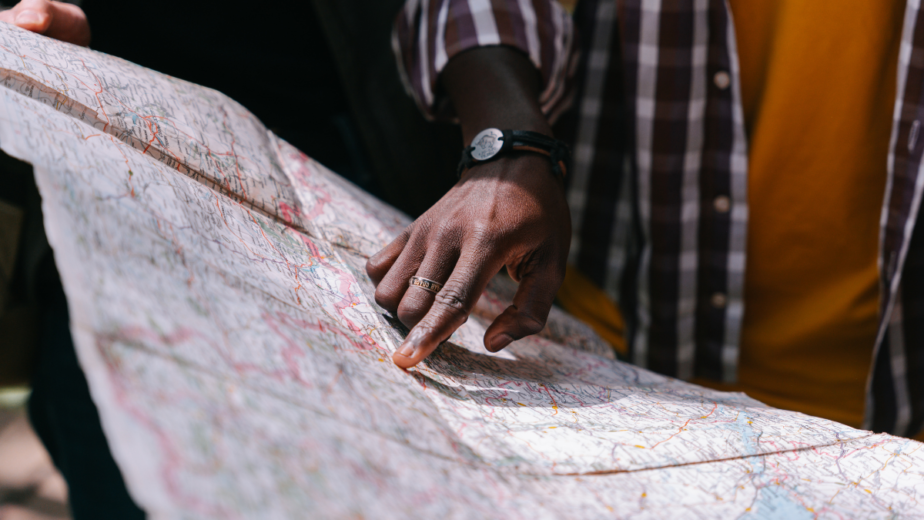 A picture of a map with a persons hand pointing at a location on the map