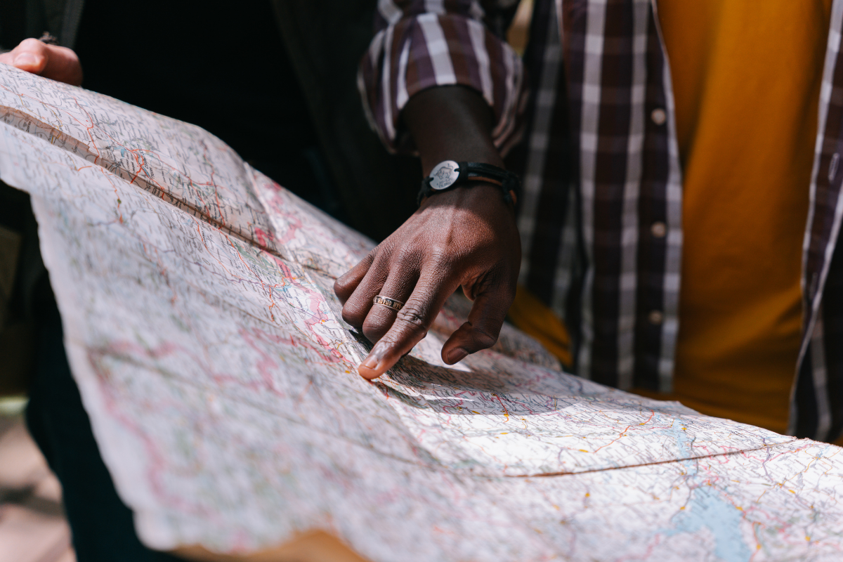 A picture of a map with a persons hand pointing at a location on the map
